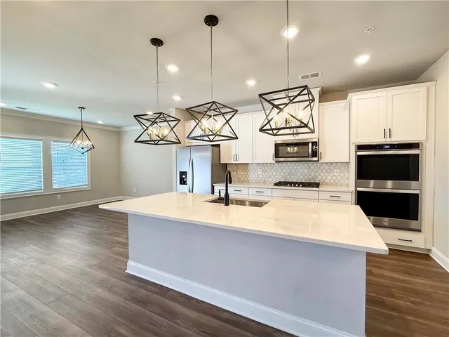 a large kitchen with stainless steel appliances a large counter top a stove and a wooden floors