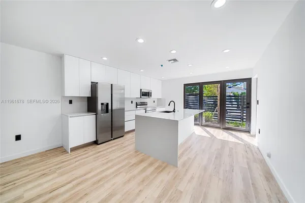 a large white kitchen with wooden floors and white walls