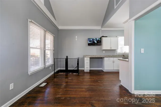 a living room with stainless steel appliances furniture a large window and a wooden floor