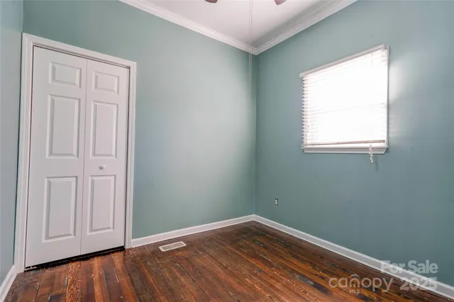 an empty room with wooden floor closet and windows