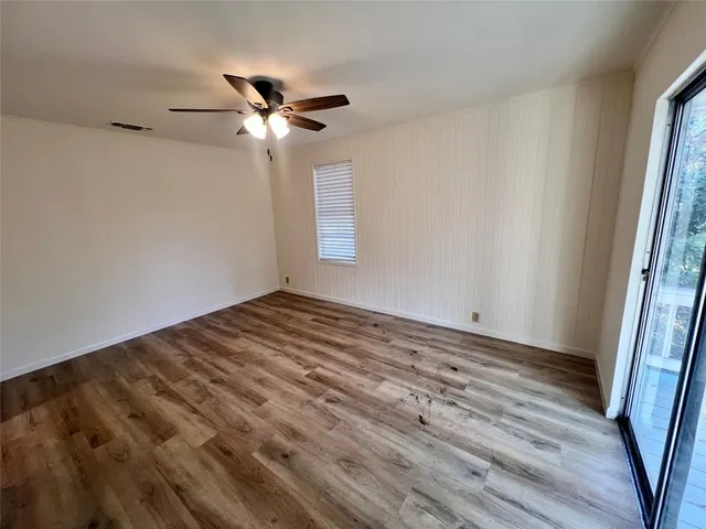 a view of empty room with wooden floor and fan