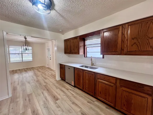 a kitchen with stainless steel appliances granite countertop wooden cabinets a sink and dishwasher with wooden floor