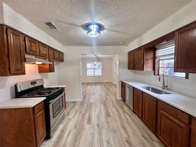 a kitchen with stainless steel appliances granite countertop a sink stove and refrigerator