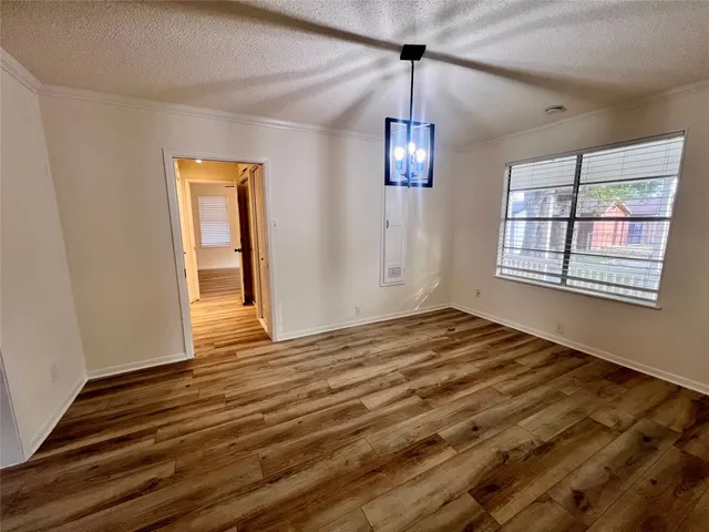 an empty room with wooden floor chandelier and windows