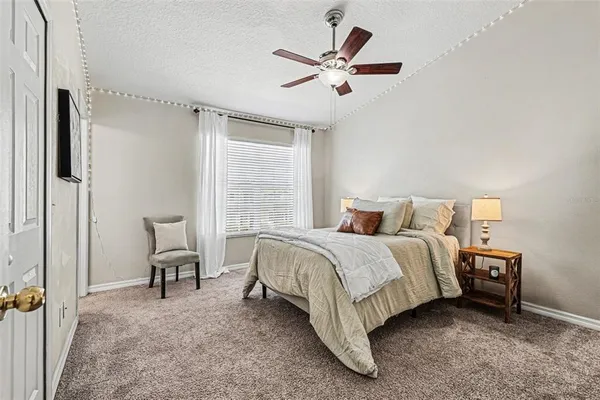 a bedroom with a bed a chair and a large window