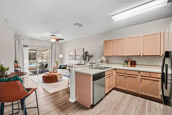 a kitchen with a stove a sink dishwasher a dining table and chairs with wooden floor