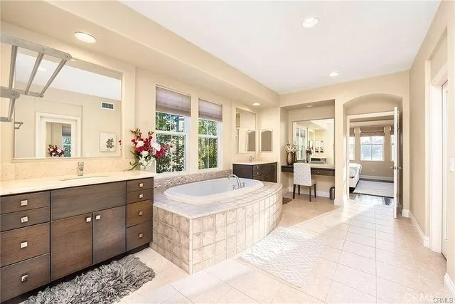 a spacious bathroom with a tub sink and mirror