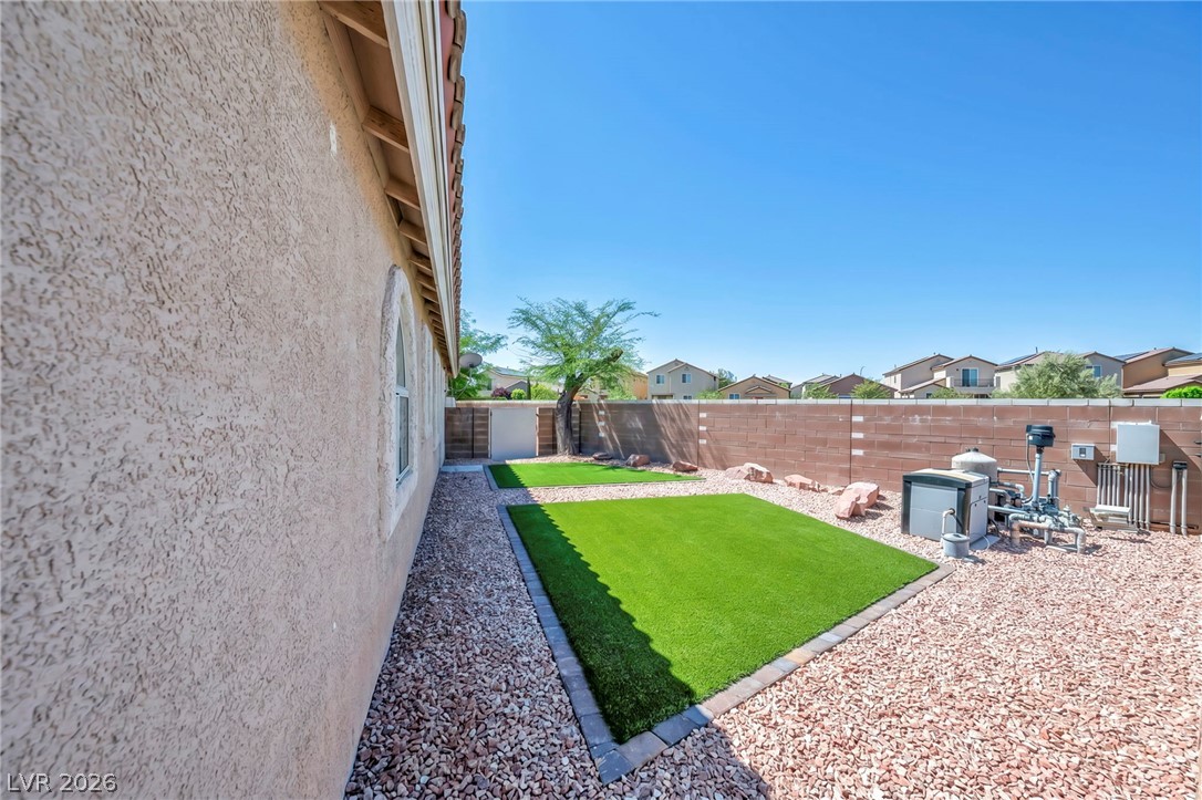6405 North Raptor Court North Las Vegas, NV 89084 - Photo 51 of 66 A well-maintained side yard with artificial turf and a private block wall offers serene outdoor living.