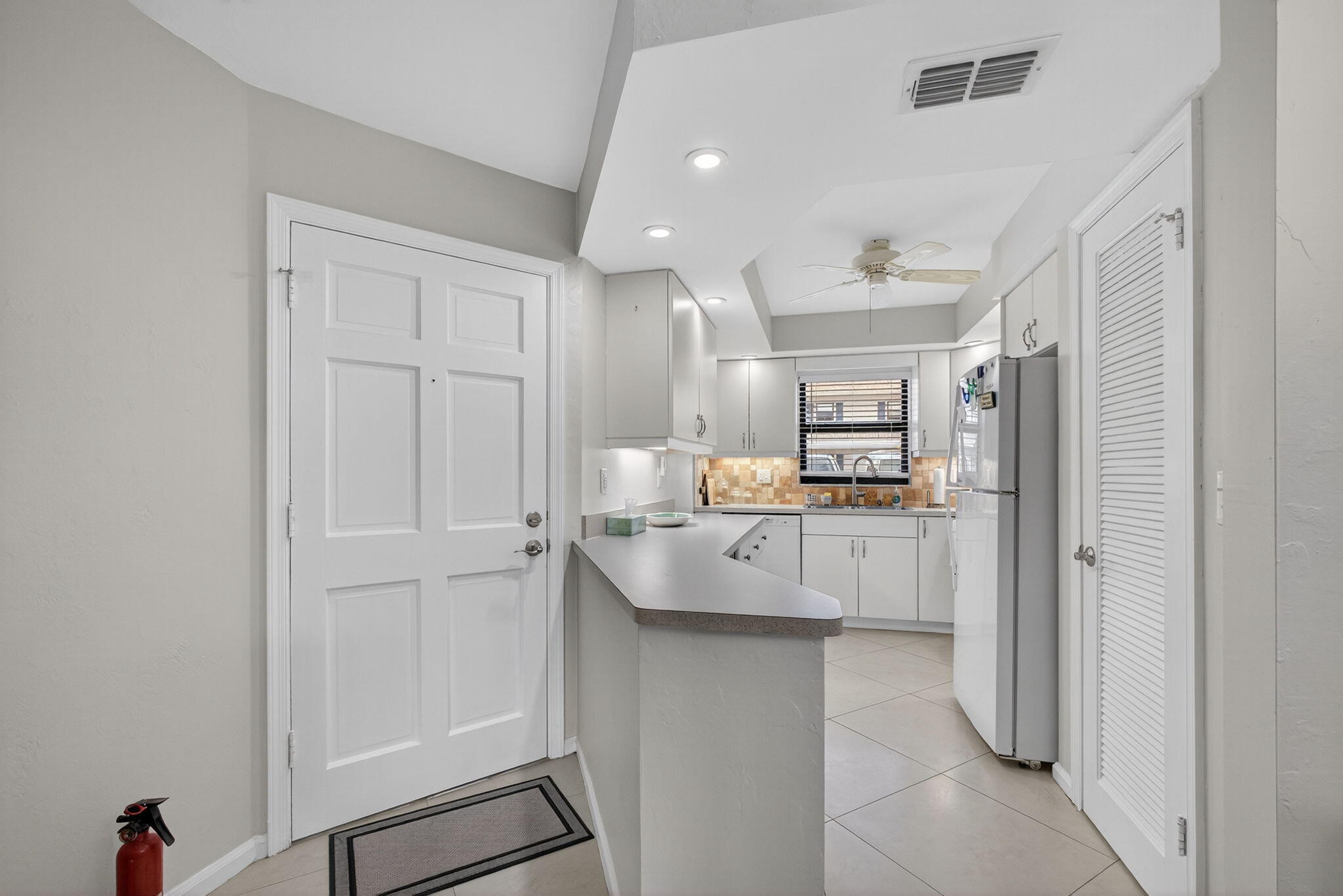 755 Saturn Street, Unit C105 Jupiter, FL 33477 - Photo 4 of 36 a large white kitchen with cabinets and stainless steel appliances
