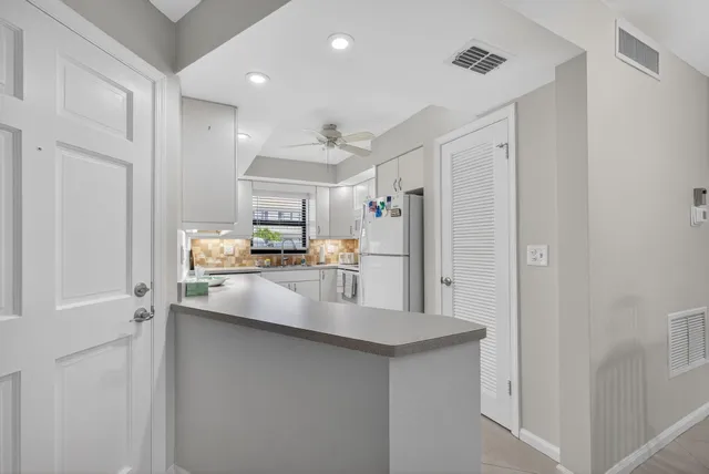 a kitchen with stainless steel appliances white cabinets sink and a window