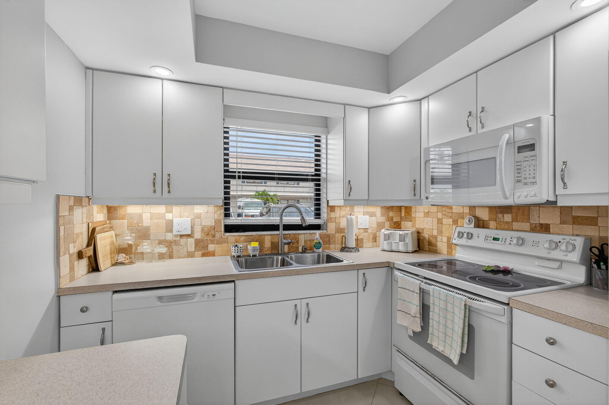 755 Saturn Street, Unit C105 Jupiter, FL 33477 - Photo 10 of 36 a kitchen with stainless steel appliances white cabinets sink and a window