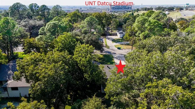 an aerial view of residential houses with outdoor space and trees all around