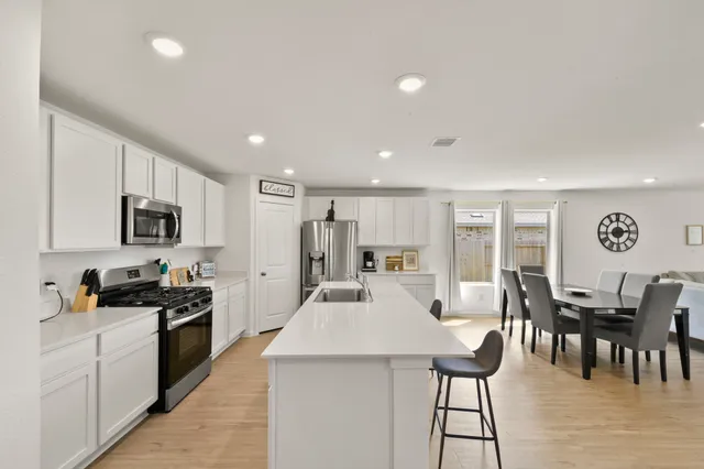 a kitchen with stainless steel appliances kitchen island granite countertop a stove a sink a dining table and chairs