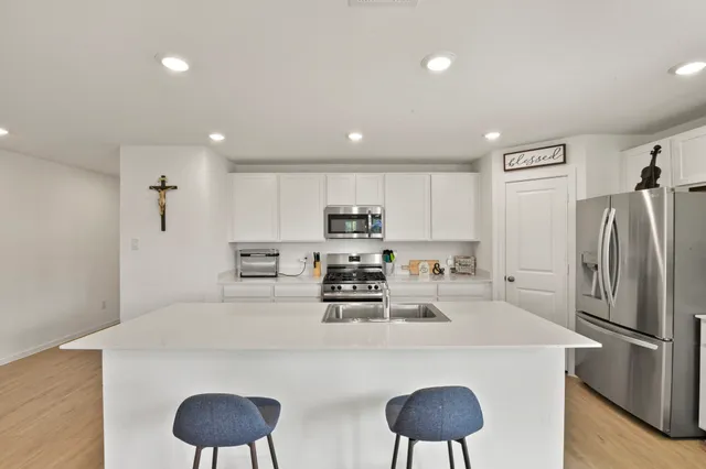 a kitchen with stainless steel appliances granite countertop a dining table chairs refrigerator and cabinets