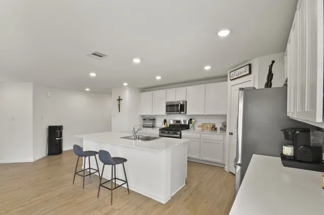 a kitchen with a refrigerator a stove top oven a sink dishwasher and white cabinets with wooden floor