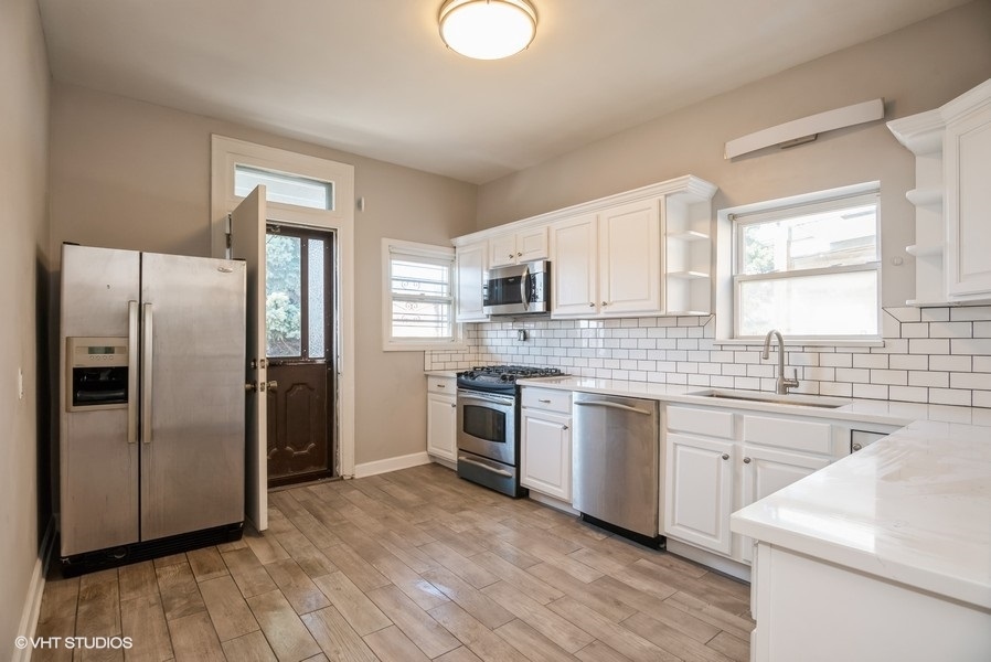 4740 North Troy Street, Unit 1 Chicago, IL 60625 - Photo 6 of 11 a kitchen with stainless steel appliances granite countertop a refrigerator a sink dishwasher a stove with wooden cabinets and floor
