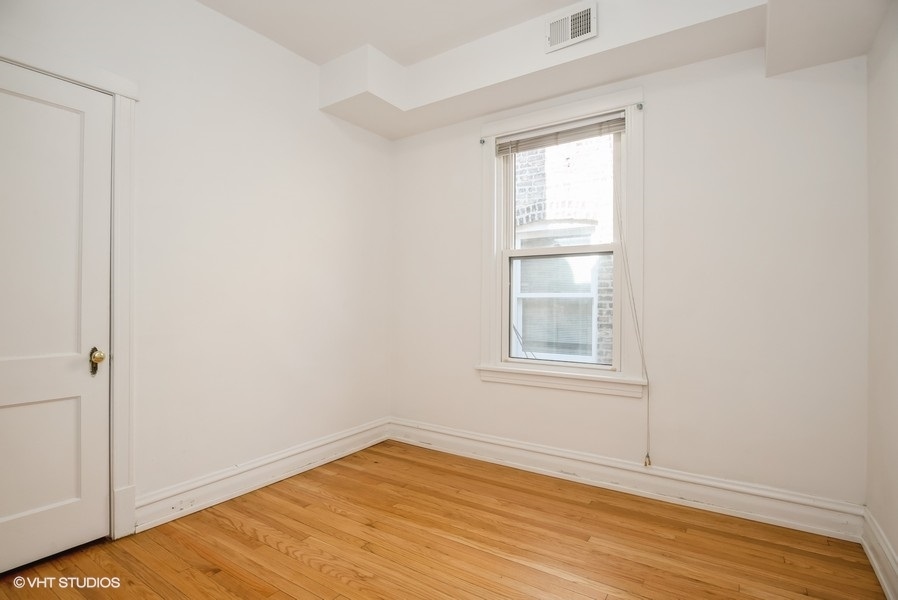 4740 North Troy Street, Unit 1 Chicago, IL 60625 - Photo 8 of 11 an empty room with wooden floor and windows