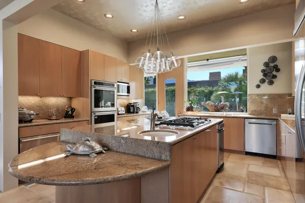 a kitchen with kitchen island granite countertop a sink stove and refrigerator