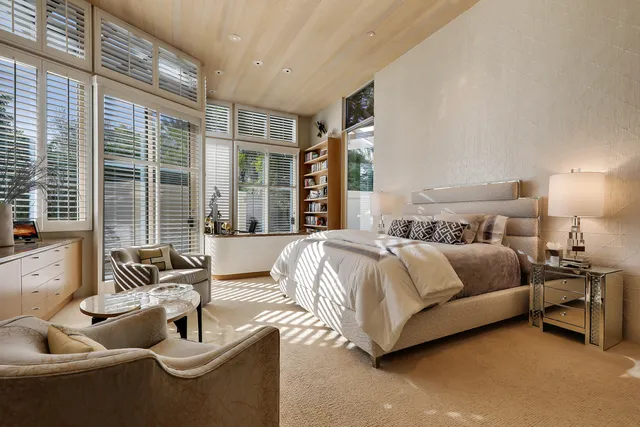 a spacious bedroom with a bed and glass walk in closet