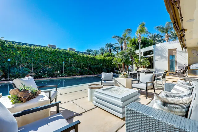 a view of a patio with couches and a table and chairs with wooden floor and fence