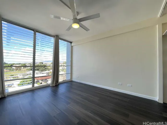 an empty room with wooden floor and windows with curtains