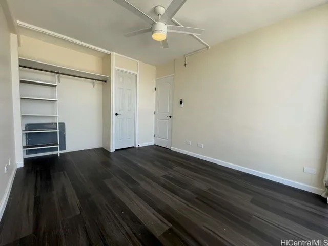 a view of an empty room with wooden floor a ceiling fan and window