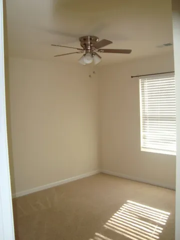an empty room with a window and a fan