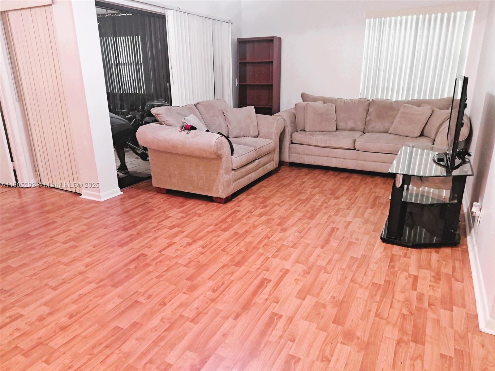 11532 Northwest 10th Street, Unit 11532 Pembroke Pines, FL 33026 - Photo 13 of 16 a living room with a bed and a wooden floor