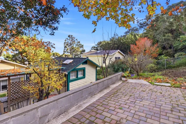 a view of a house with a small yard and a large tree