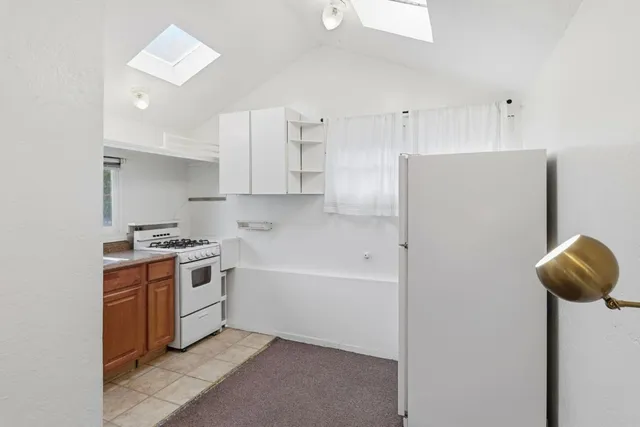 a kitchen with stainless steel appliances granite countertop a refrigerator a sink a stove and white cabinets