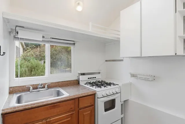 a view of a kitchen stove a sink and dishwasher with wooden floor