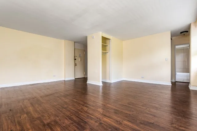 a view of an empty room with wooden floor and a window