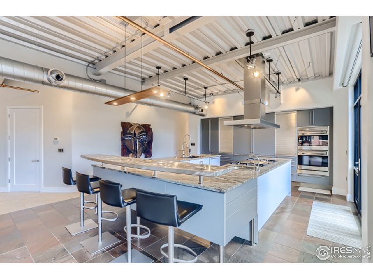 1360 Walnut Street, Unit 301 Boulder, CO 80302 - Photo 9 of 40 a kitchen with stainless steel appliances kitchen island a table chairs in it and wooden floors