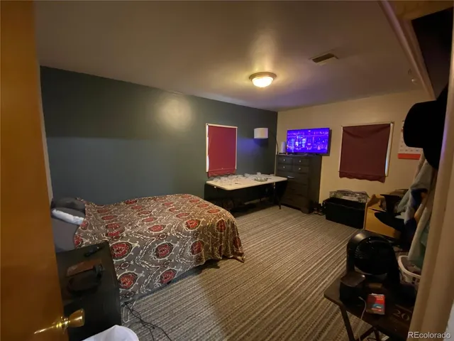 a bedroom with bed and a flat tv screen on dresser