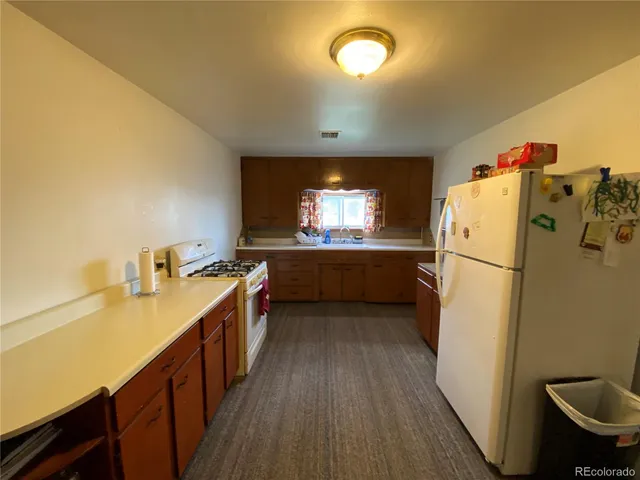 a kitchen with a refrigerator a sink and wooden floor