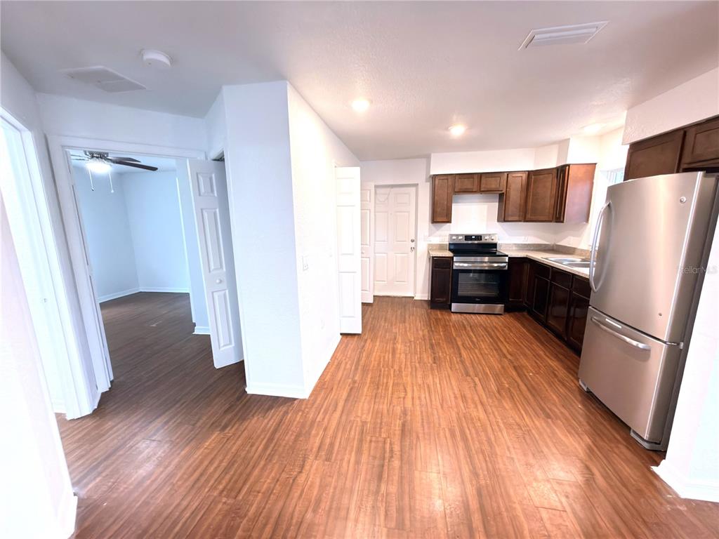 33 Sand Mountain Road Fort Meade, FL 33841 - Photo 2 of 9 a kitchen with stainless steel appliances a refrigerator a sink dishwasher a stove and white cabinets with wooden floor