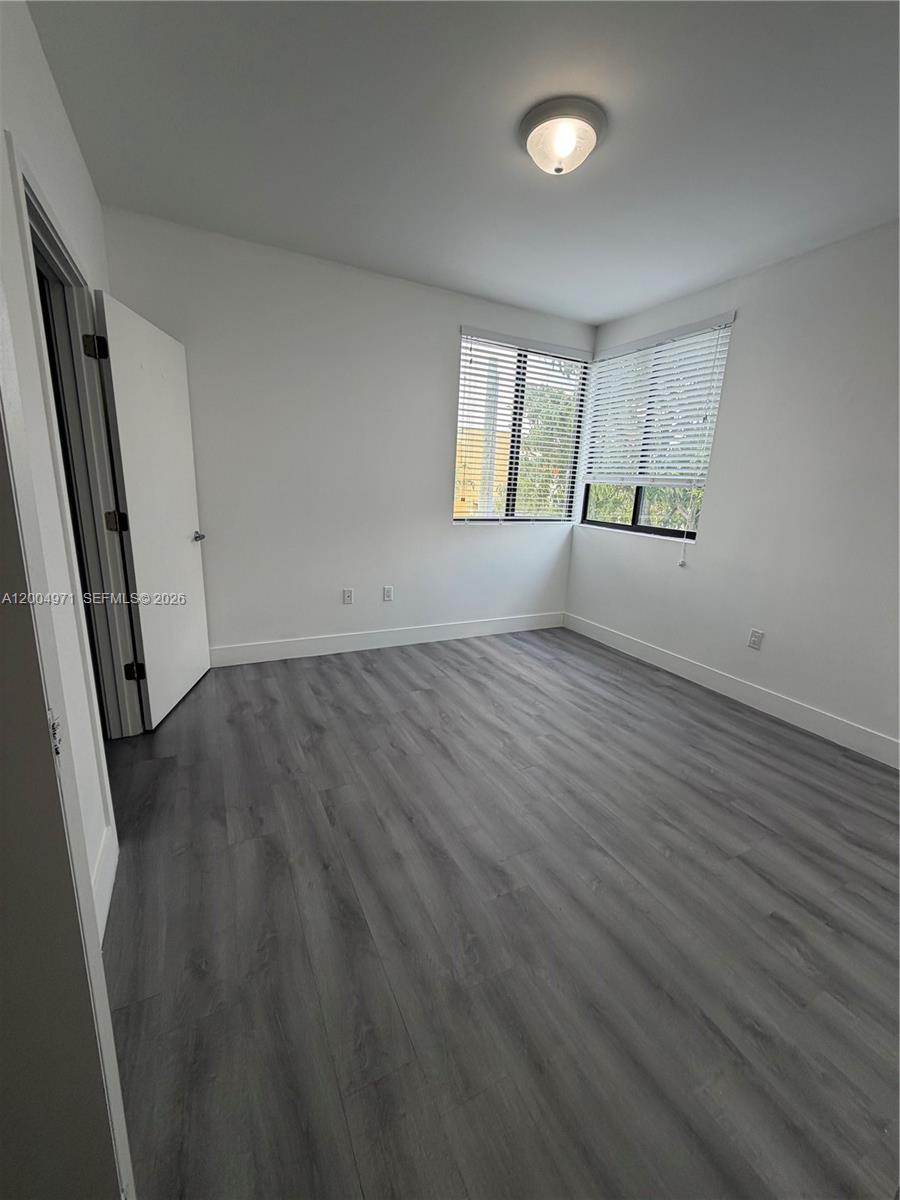 853 East 24th Street, Unit 203 Hialeah, FL 33013 - Photo 12 of 13 an empty room with wooden floor and windows