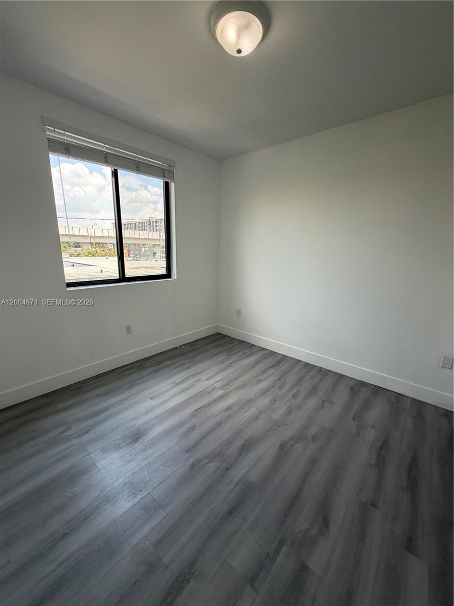 853 East 24th Street, Unit 203 Hialeah, FL 33013 - Photo 7 of 13 an empty room with wooden floor and windows