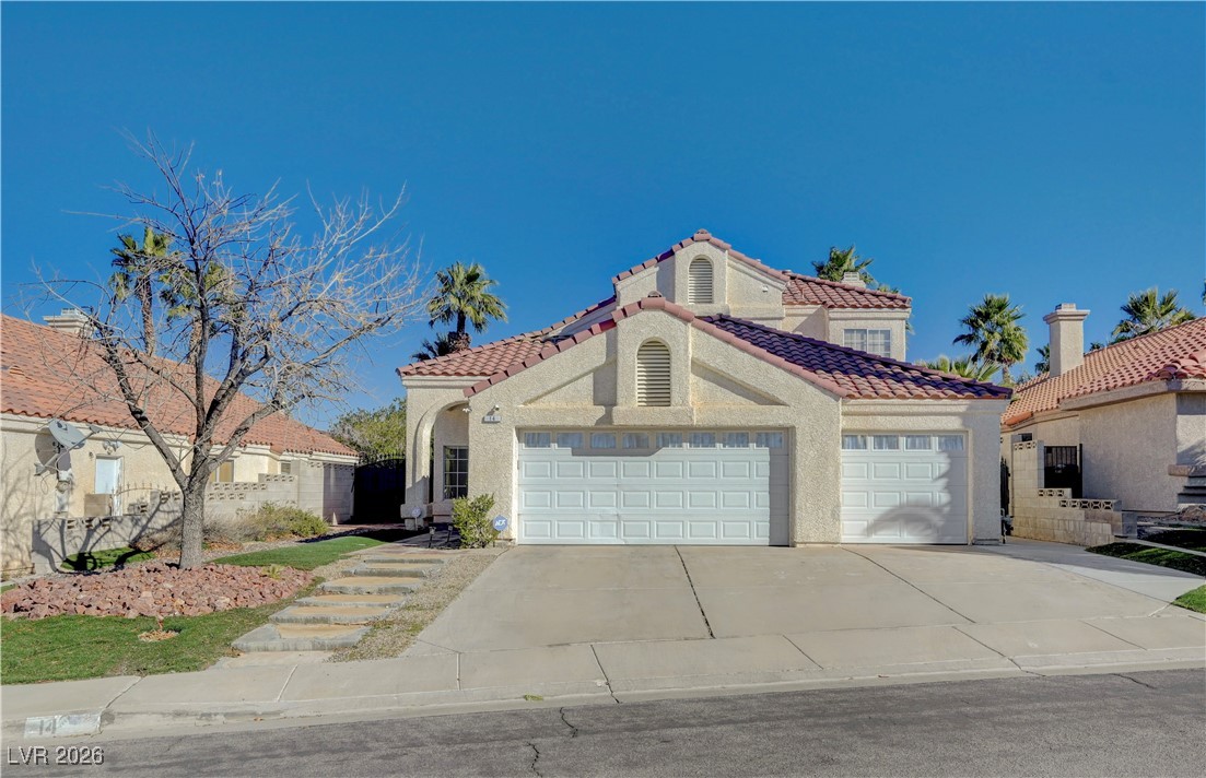 Mediterranean / spanish home featuring driveway, a garage, stucco siding, and a tile roof