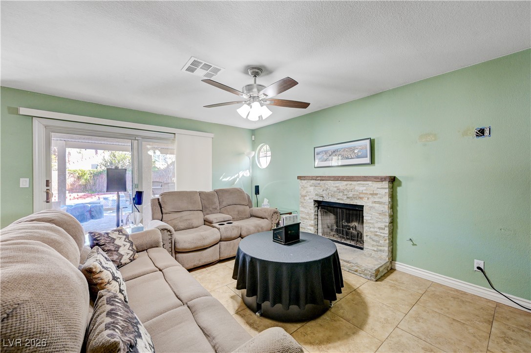 14 Barton Spring Circle Henderson, NV 89074 - Photo 17 of 64 Living area with a fireplace, light tile patterned flooring, a ceiling fan, and a textured ceiling