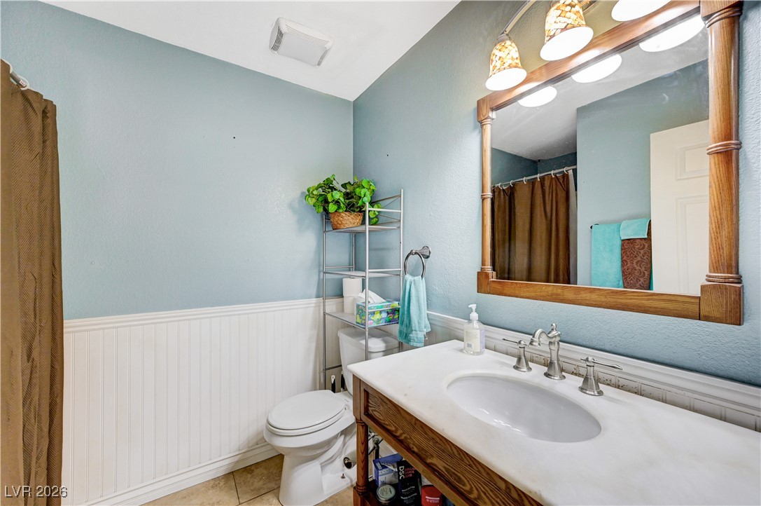 14 Barton Spring Circle Henderson, NV 89074 - Photo 21 of 64 Shower with wainscoting, vanity, light tile patterned flooring, and a shower with curtain