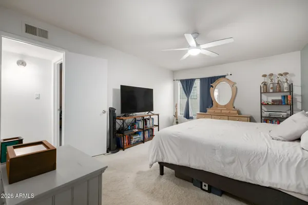 a bedroom with a bed and a flat tv screen on dresser