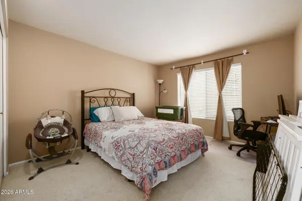 a bedroom with a bed chair and windows