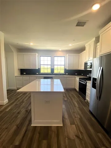 a kitchen with kitchen island a stove a table and chairs in it