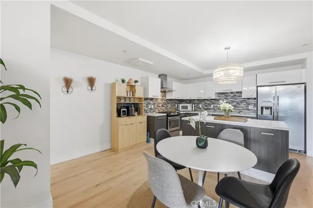 a kitchen with stainless steel appliances granite countertop a dining table chairs and white cabinets
