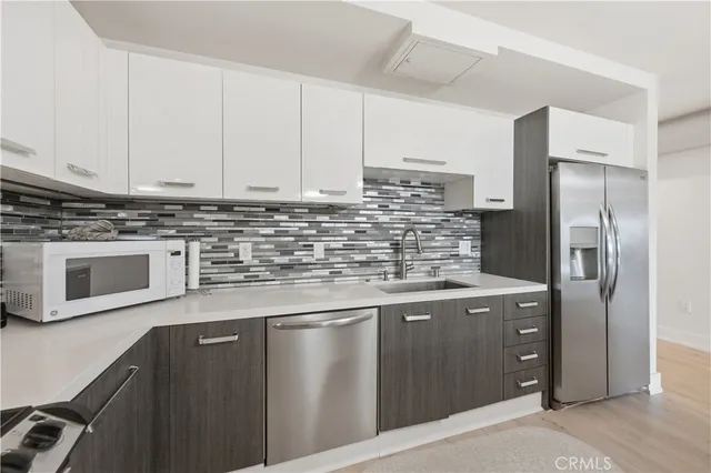 a kitchen with stainless steel appliances granite countertop a refrigerator a stove and a sink