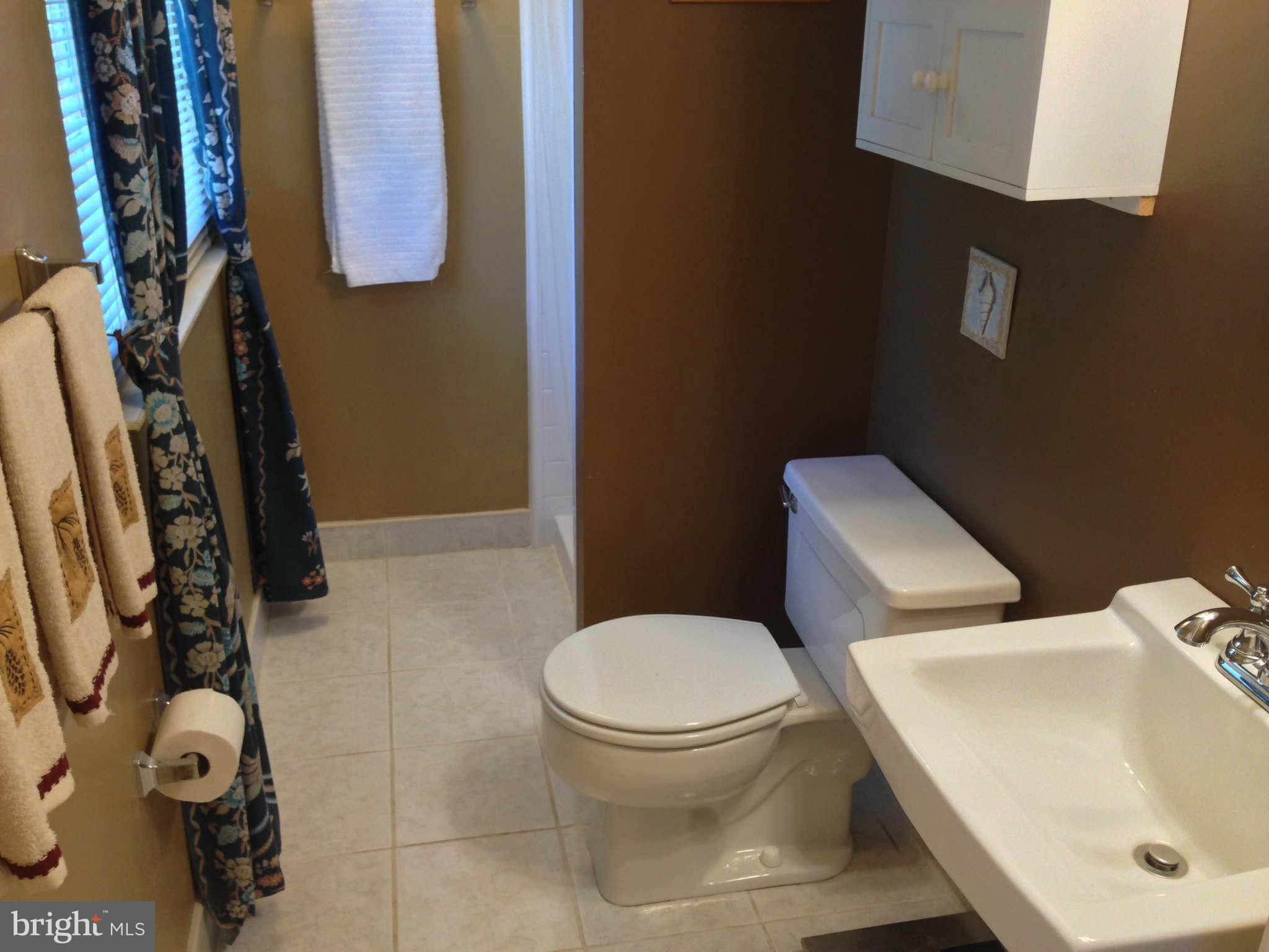 8066 Athena Street Springfield, VA 22153 - Photo 18 of 30 a white toilet sitting next to a bathroom sink and a mirror
