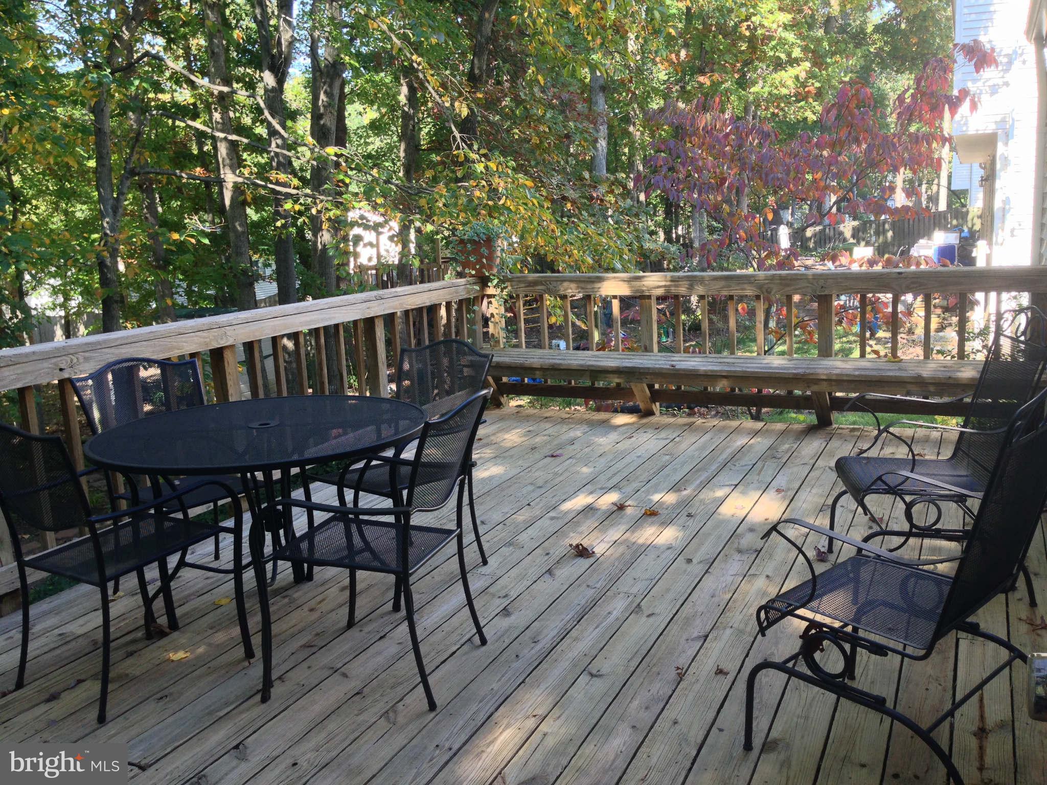 8066 Athena Street Springfield, VA 22153 - Photo 27 of 30 a view of a patio with table and chairs with wooden floor and fence
