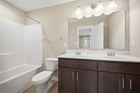 a bathroom with a toilet a sink a mirror a bathtub and vanity