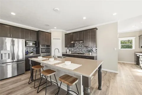 a kitchen with stainless steel appliances a dining table chairs and wooden floor